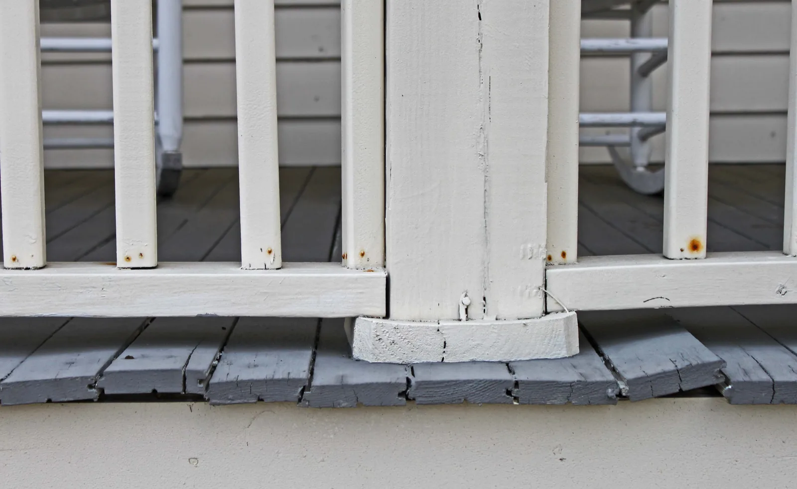 Warped, separating deck boards at the base of a white porch column